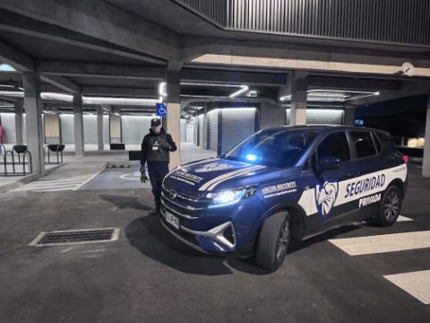 Guardia de ASCOR Security y vehículo institucional en un estacionamiento techado